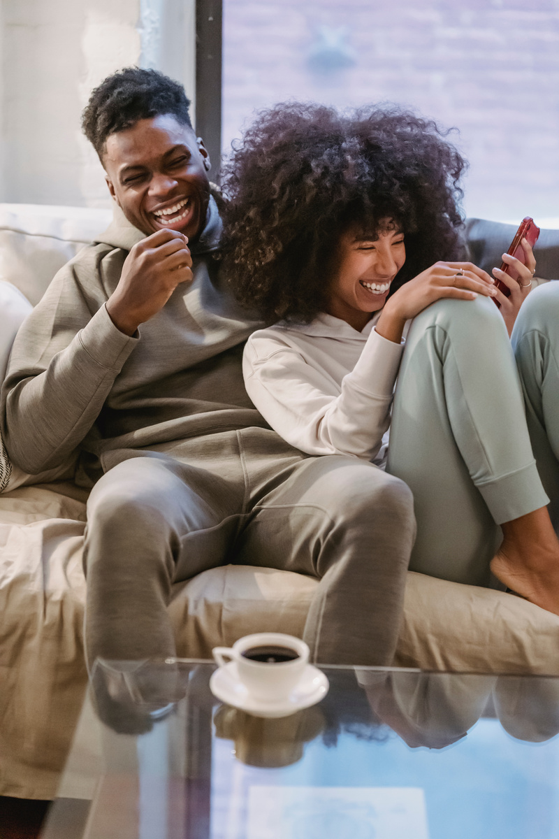 Happy black couple on couch with smartphone