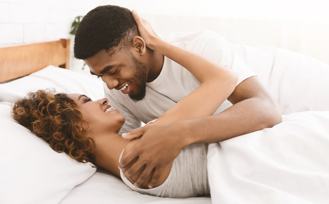 Loving black couple relaxing on bed at home,